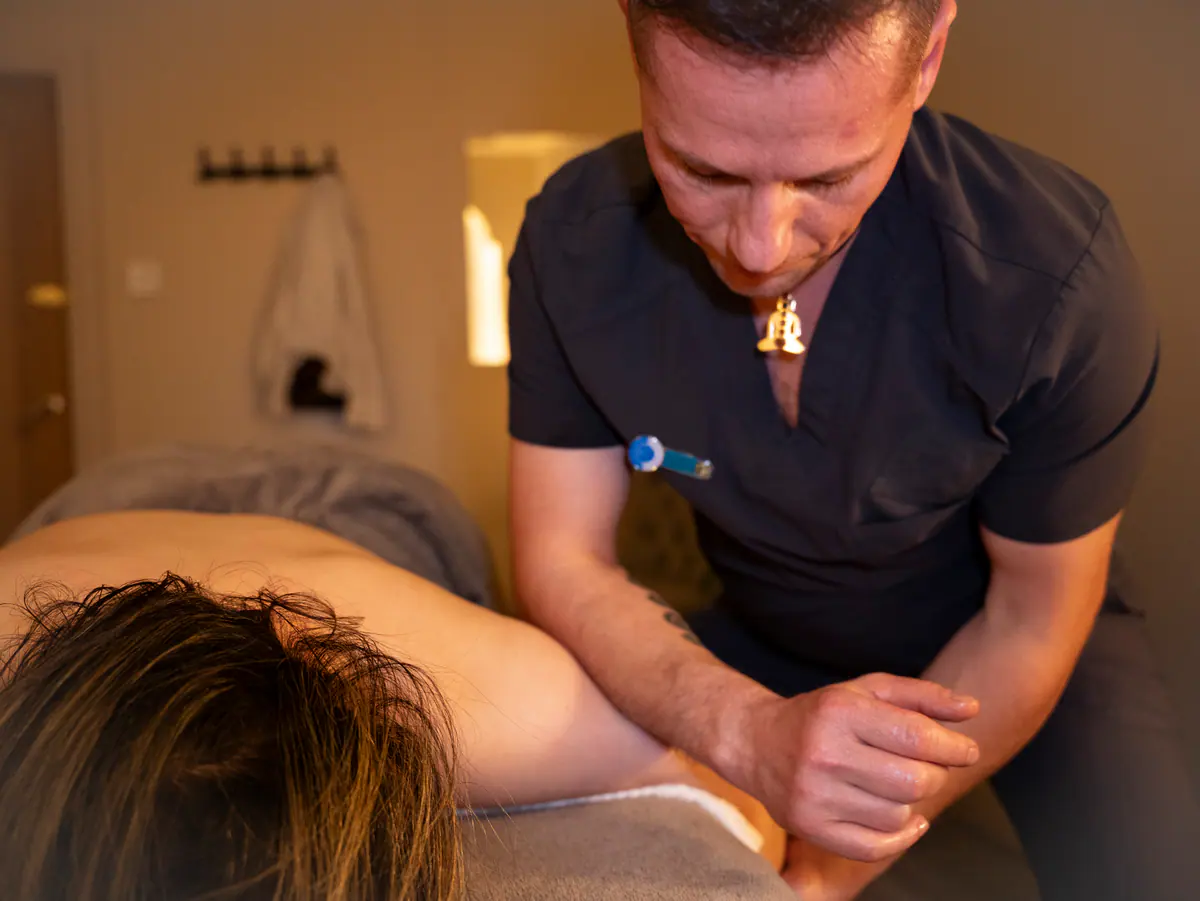 A therapist working a forearm into a client's shoulder during a deep tissue massage