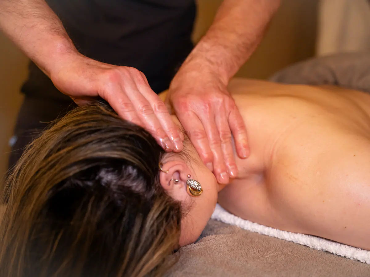 Two hands resting at the base of a client's head during a scalp and neck massage